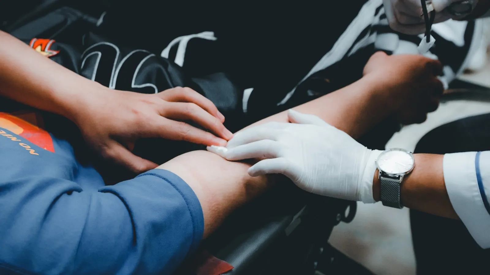 Zorgverlener met handschoenen verzorgt een arm na een bloedafname.