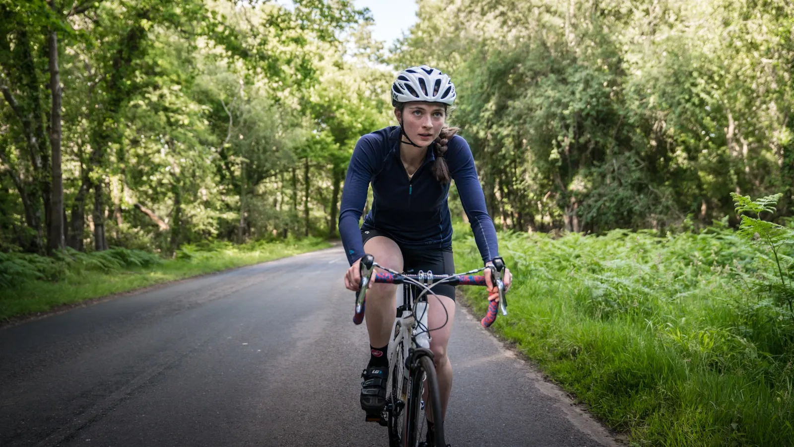 Wielrenster fietst op een landweg tussen het groen.