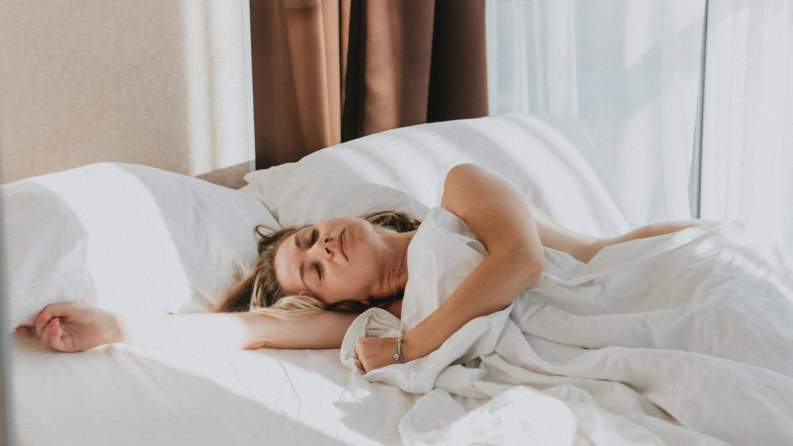Iemand ligt uitgerust in bed, met de nadruk op slaap en herstel.