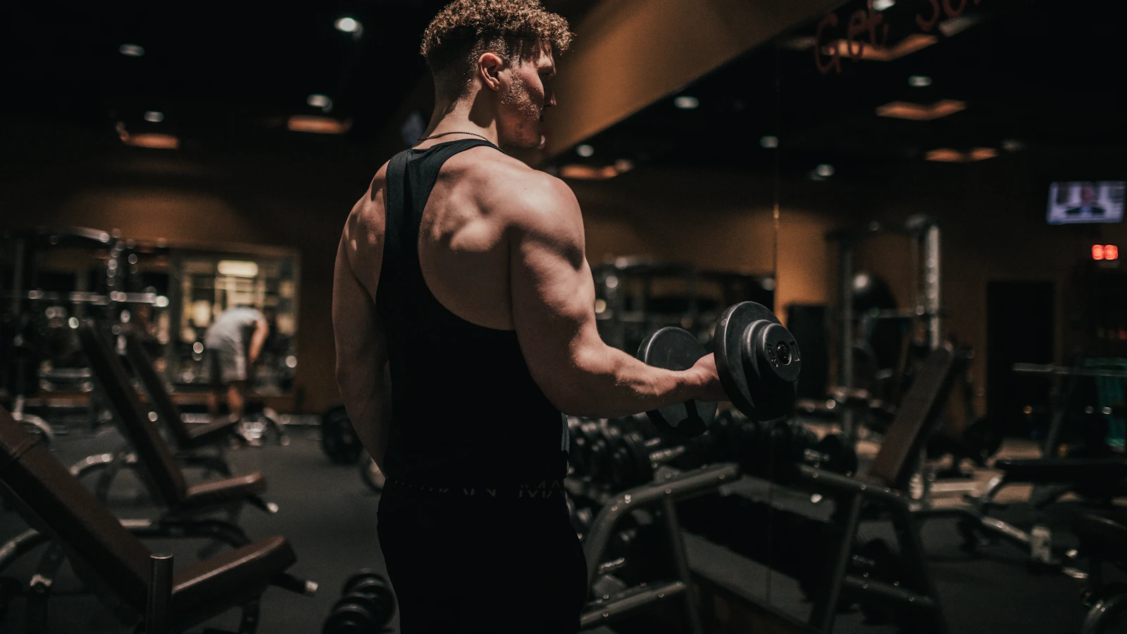 Een sporter houdt een dumbbell vast in een sportschool.