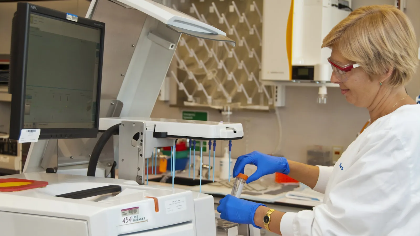 Laborant in een witte jas verwerkt buisjes bloed aan een laboratoriumapparaat.