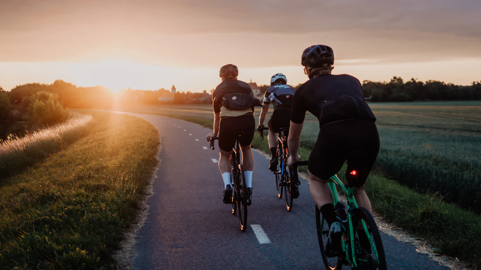 Wielrenners op de weg bij zonsopkomst.
