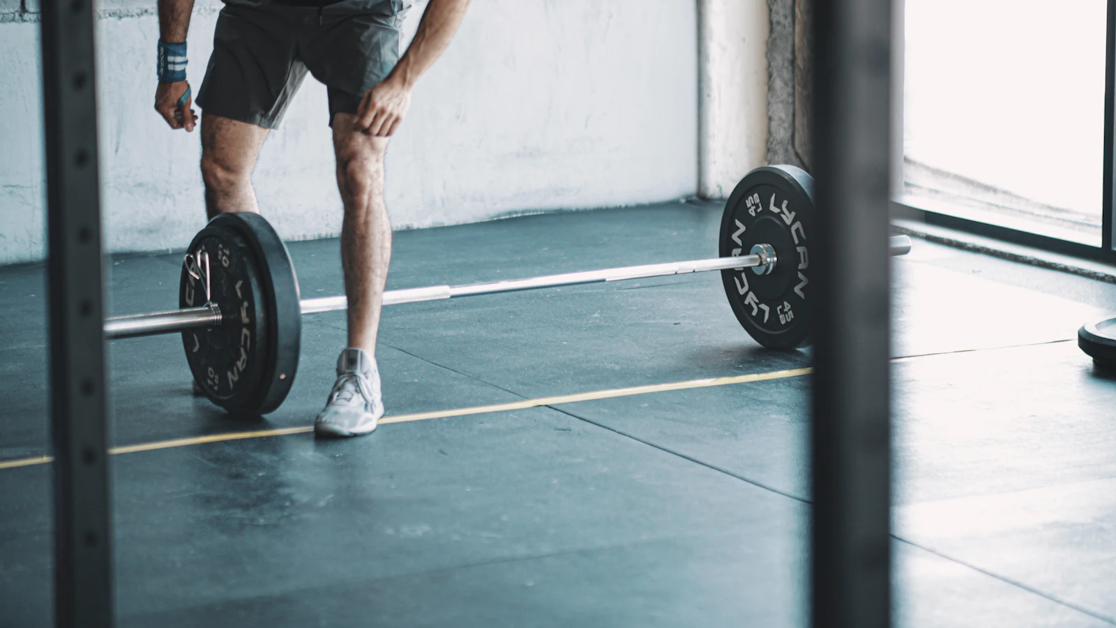 Sporter tilt een halterstang op in een donkere sportschool.