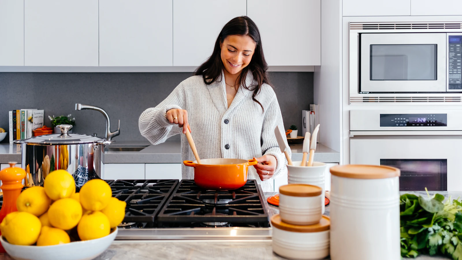 Someone stirring a pot on the stove in a bright kitchen.