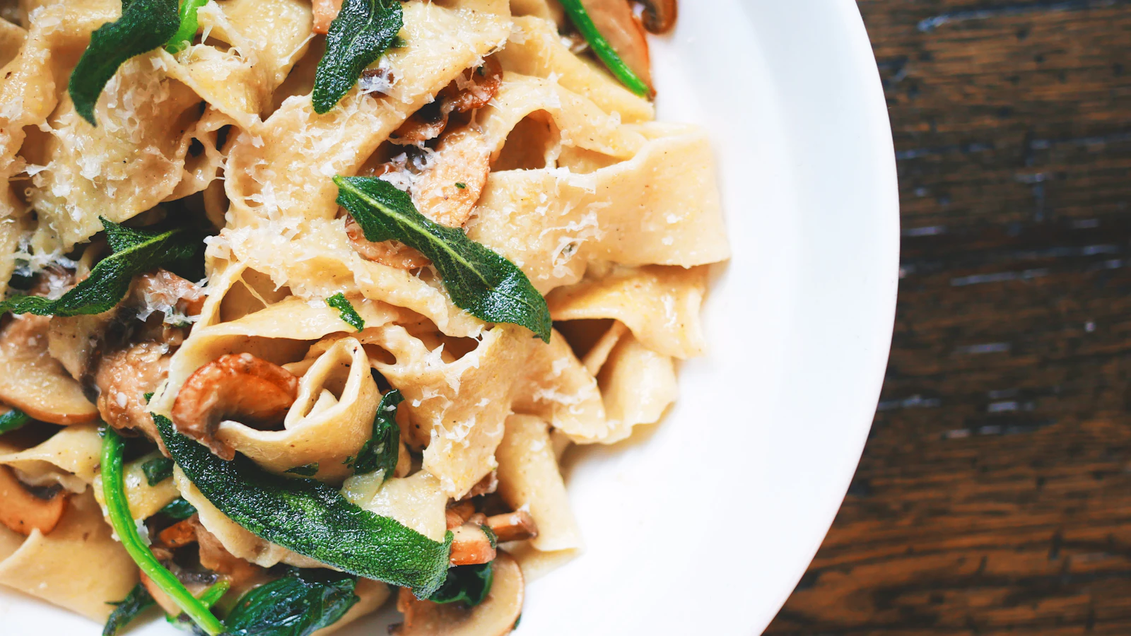 A plate of fresh pasta with vegetables and herbs.