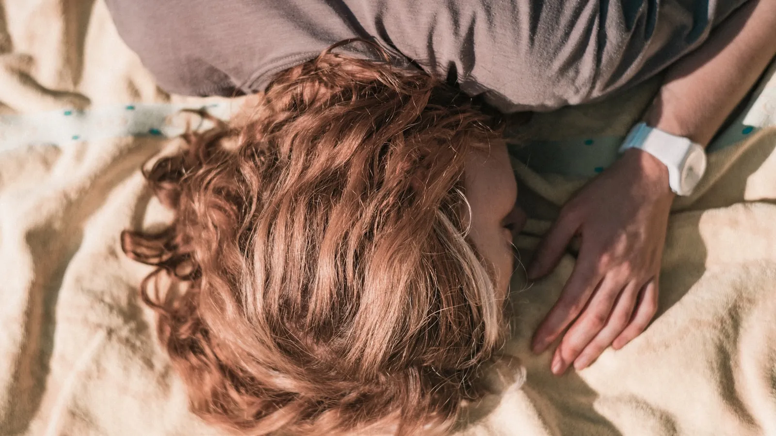 Iemand ligt te slapen in bed, van bovenaf gefotografeerd.