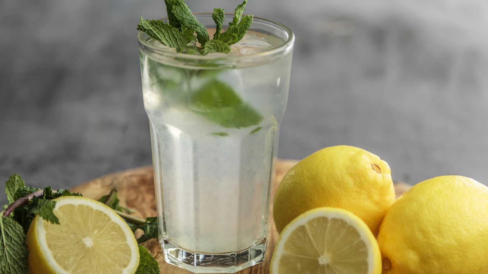 A glass of water with lime beside fresh lime slices.
