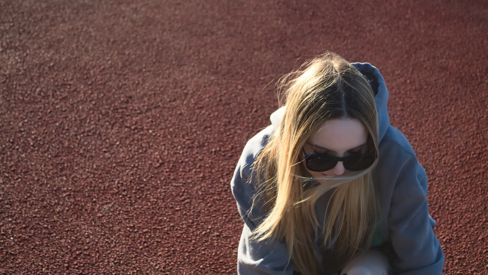 Hardloopster zit uit te rusten op een atletiekbaan na haar training.
