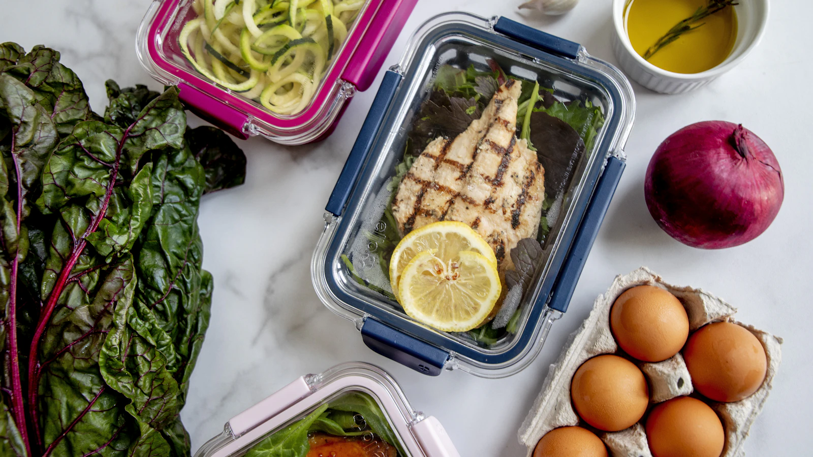 Een meal prep bakje met gegrilde kip, eieren en groenten.