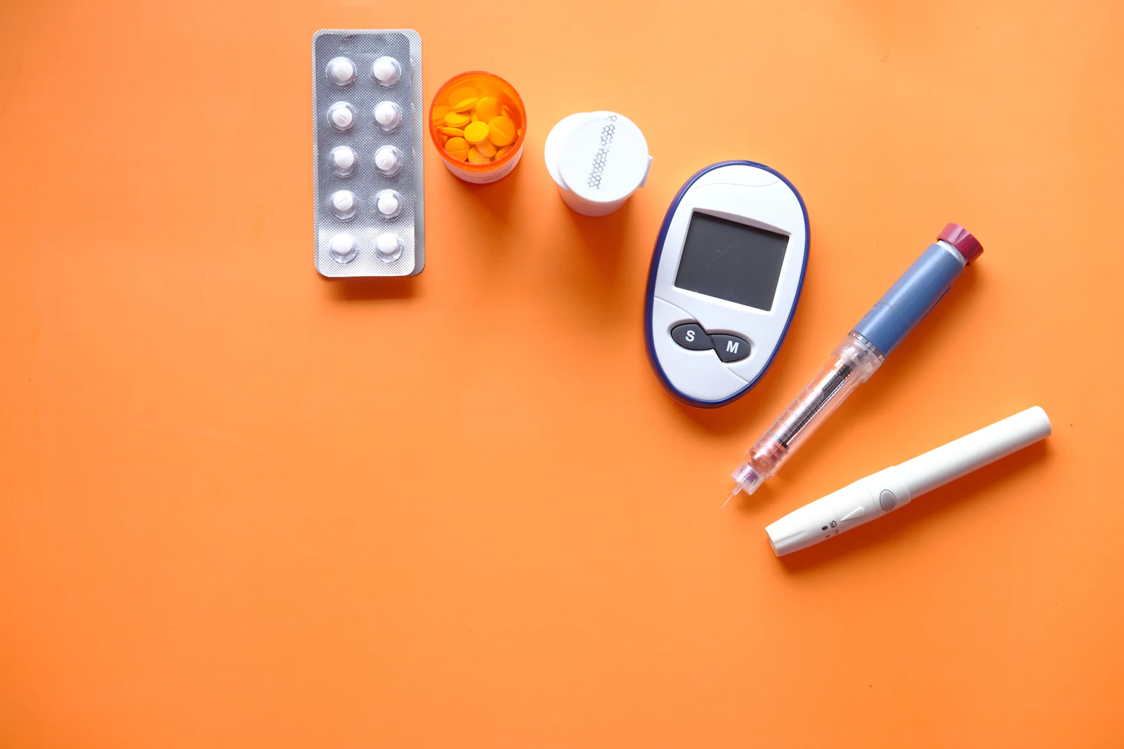 Digitale bloedglucosemeter met teststrip op een lichte ondergrond.