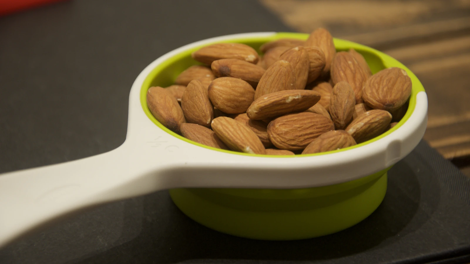 A bowl of almonds on a dark table. Nuts are one of the foods that contain magnesium.
