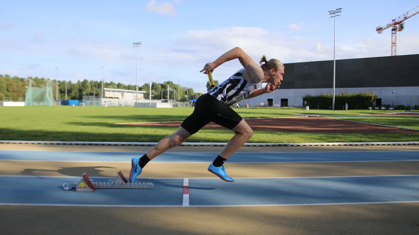 Sprinter komt uit de startblokken op een atletiekbaan.