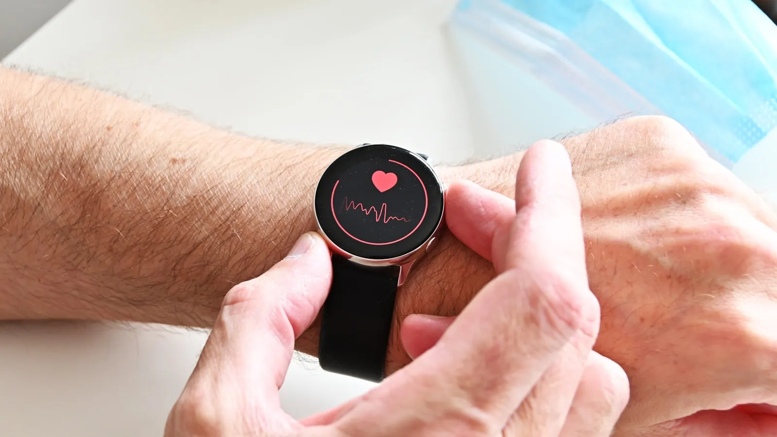 Hand bedient een smartwatch die een hartslagmeting op het scherm toont.