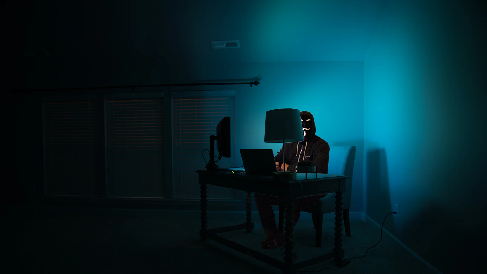 Een man werkt geconcentreerd achter een laptop aan een bureau.