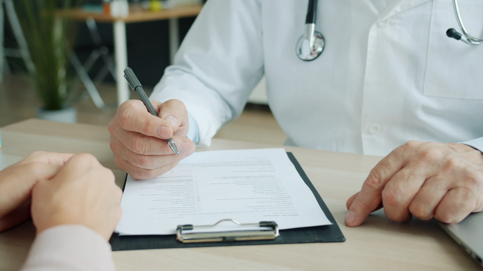 Arts noteert gegevens op een patientenkaart.