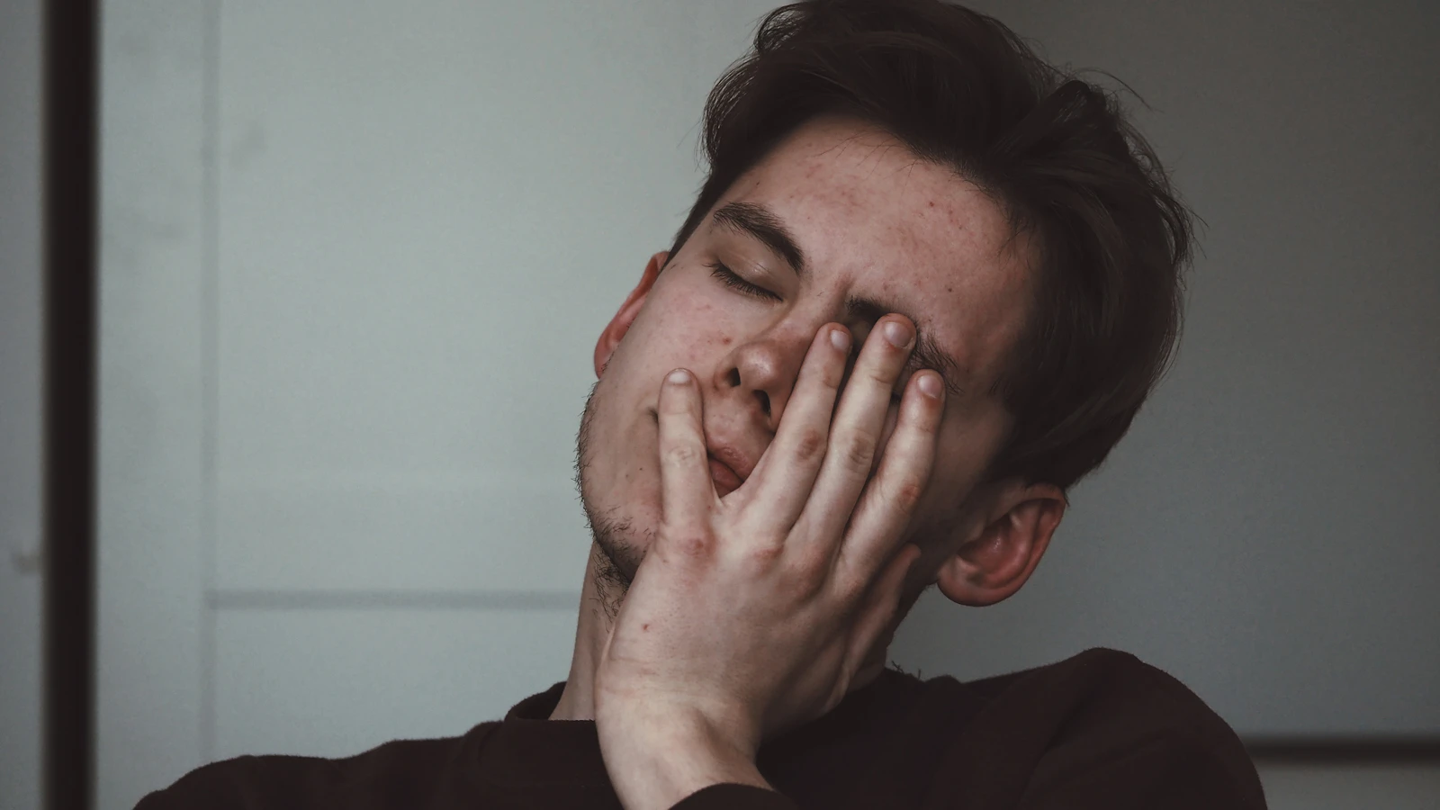Vermoeide man met zijn hand tegen zijn hoofd.