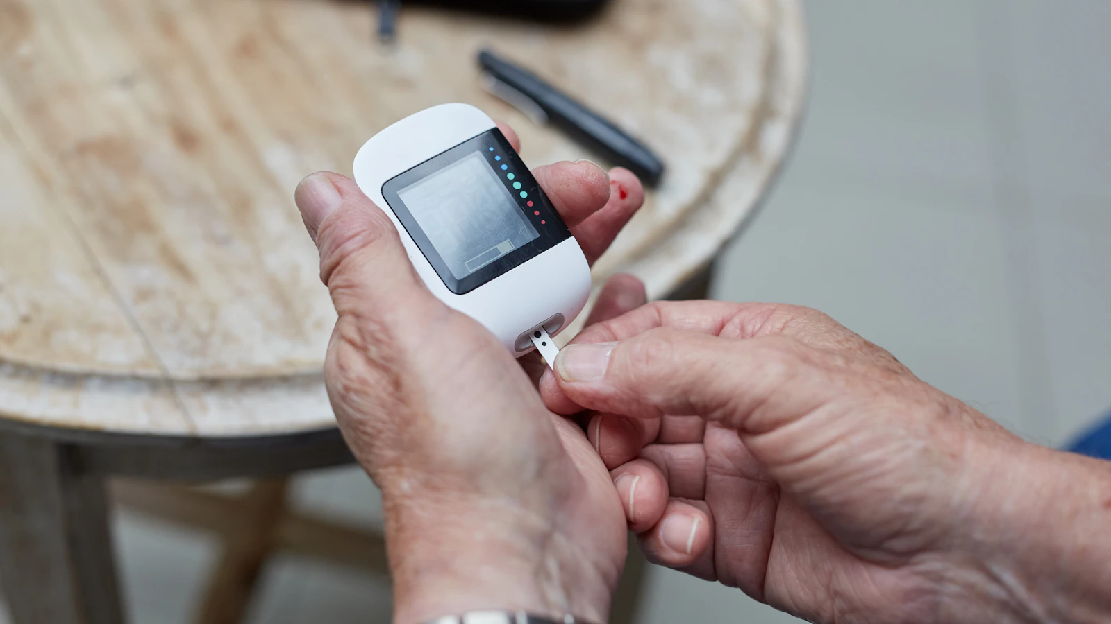 Iemand meet de bloedsuiker met een glucosemeter en een vingerprik.